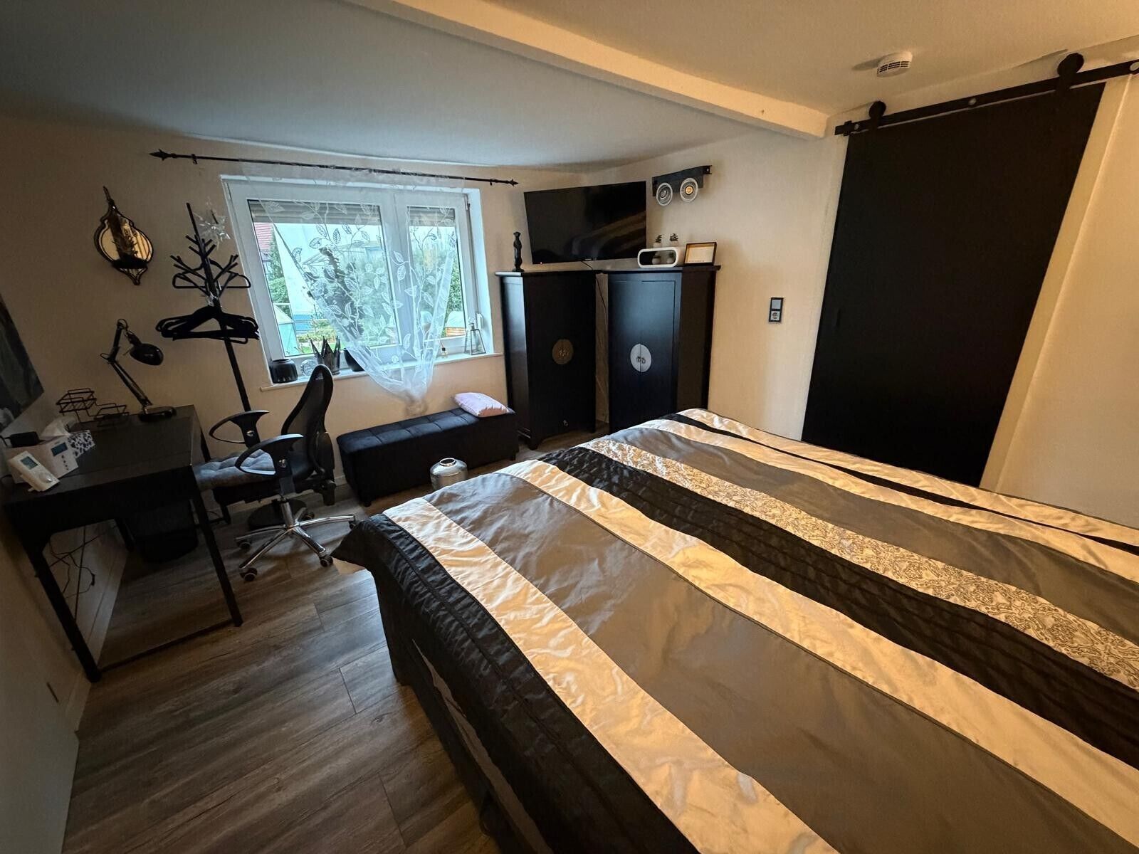 Ein Schlafzimmer mit Bett, Schreibtisch, Stuhl und einem Fenster mit Aussicht.