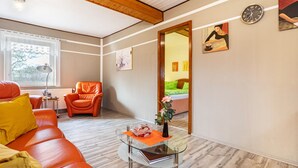 Una sala de estar moderna con una mesa de centro de vidrio, un sofá de cuero y techo de madera.