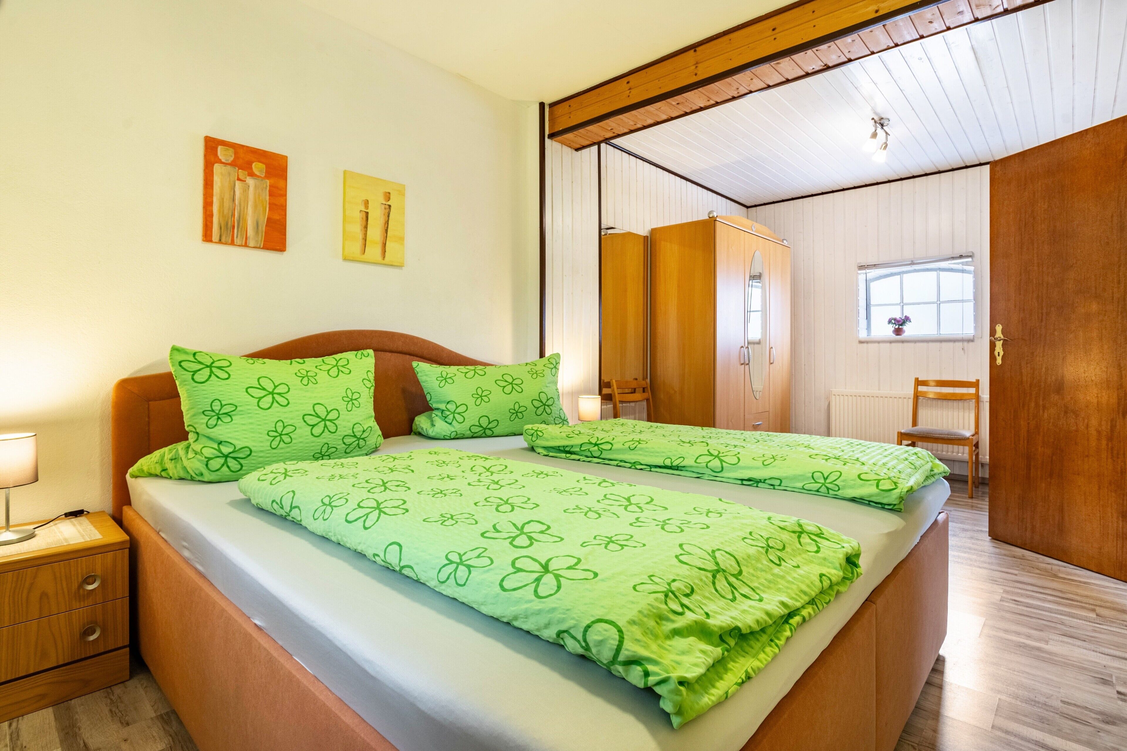 Ein Schlafzimmer mit einem Bett, zwei Nachttischen, einem Kleiderschrank und einem Fenster.