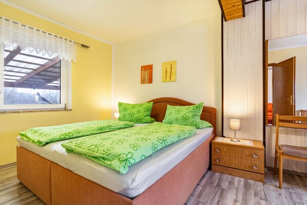 Une chambre à coucher comprenant un lit, une table de chevet, une chaise et deux tableaux accrochés au mur.