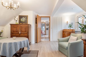 Une pièce comprenant une table à manger, un canapé, un meuble en bois et une porte donnant sur une autre pièce.
