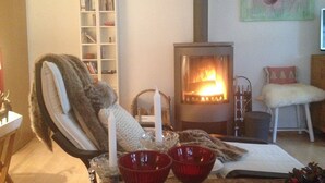 A cozy living room with a fireplace, a bookshelf, and a comfortable chair.
