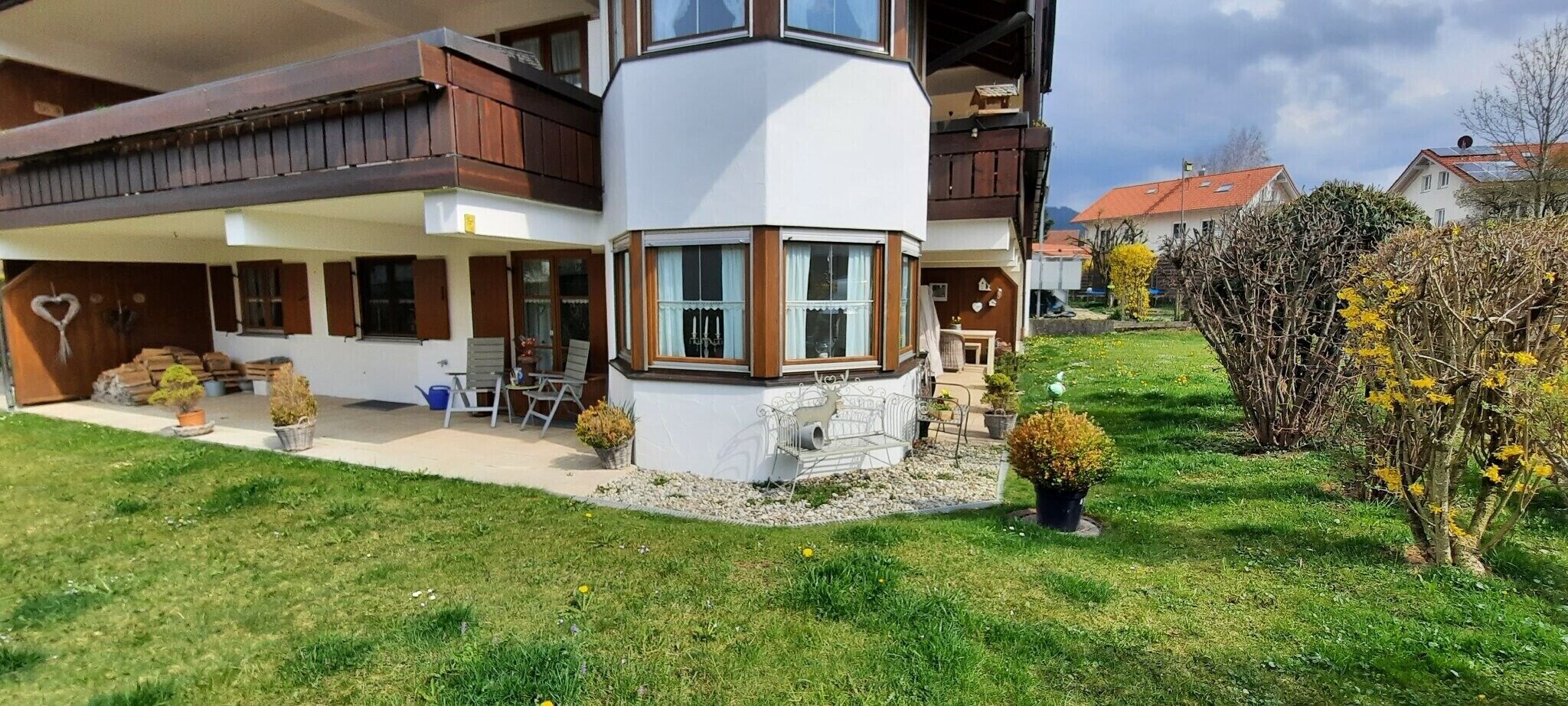 Een huis met twee verdiepingen, een balkon, een overdekte patio en een verzorgd gazon.
