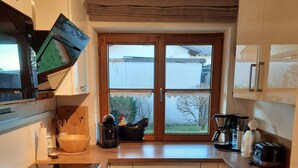 A kitchen with a large window, wooden cabinets, a stove, and various kitchen appliances.