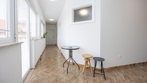 A hallway with a tiled floor, a round table with a stool, and a potted plant on a windowsill. - Beautiful apartment in Vinjani Donji with WiFi (Vinjani Donji)