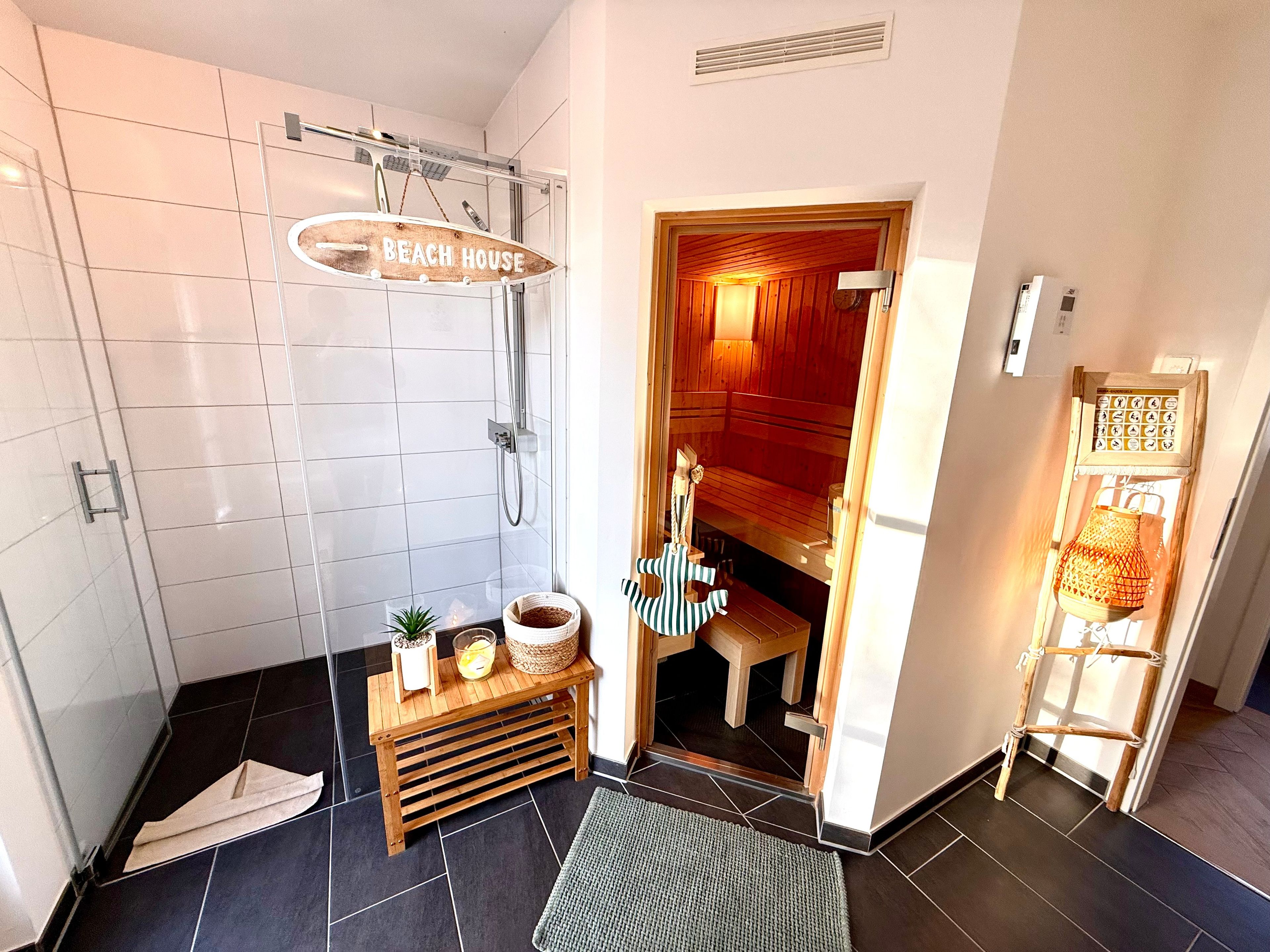 A bathroom with a shower, a wooden bench with a towel, and a small table with a plant and a basket.
