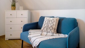 A room with a blue sofa, a white dresser with drawers, a small potted plant, and a patterned throw blanket. - Holiday Home Mühlenperle with Private Terrace, Garden, Sauna & Parking, Baltic Sea, Stove (Boiensdorf OT Stove)