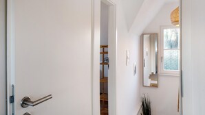 A hallway with a white door, a wooden staircase, and a window with a view of trees. - Holiday Home Mühlenperle with Private Terrace, Garden, Sauna & Parking, Baltic Sea, Stove (Boiensdorf OT Stove)