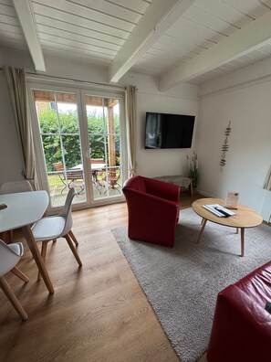A modern living room with a red sofa, a white table, and a wooden coffee table.