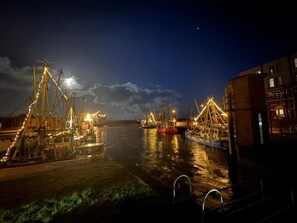 A nighttime harbor with boats docked, illuminated by artificial lights.