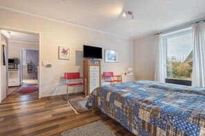 A bedroom with a bed, a TV, a desk, and a window.