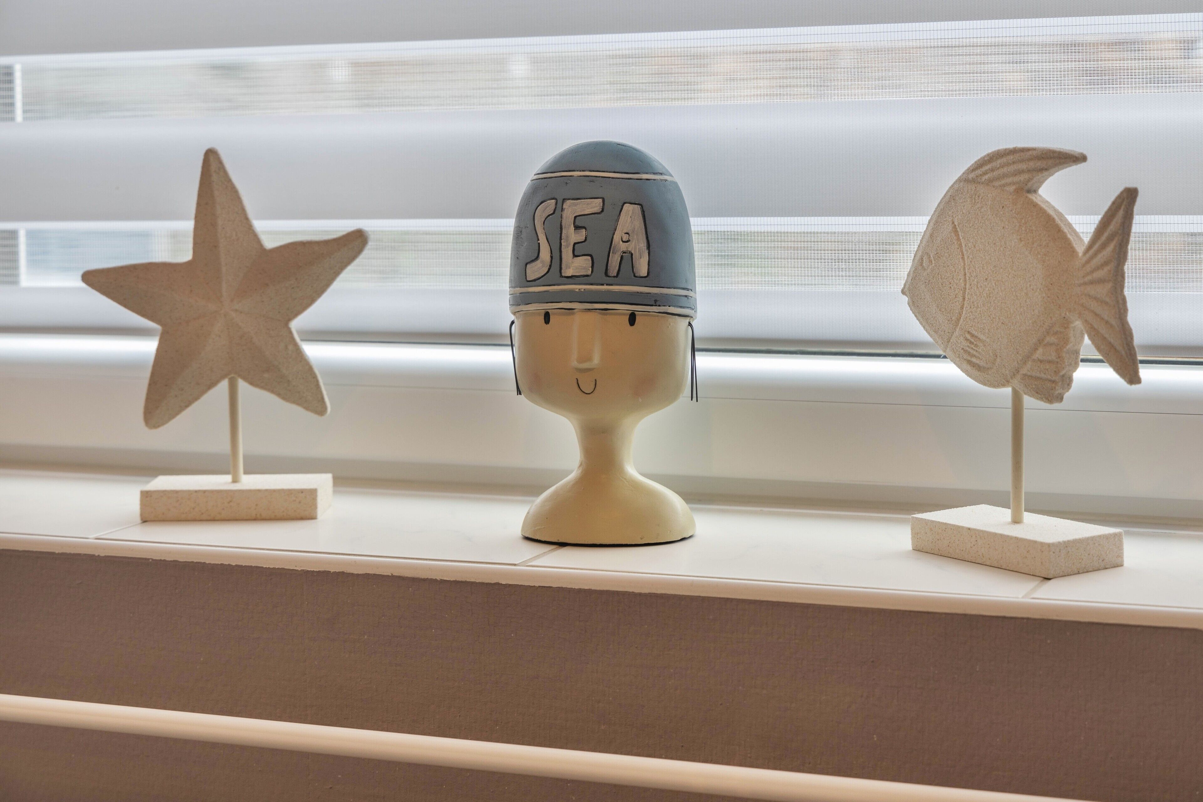 Three decorative items on a shelf: a star, a helmet with 'SEA' on it, and a fish.