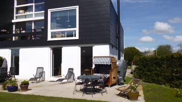 Een modern huis met twee verdiepingen, een balkon, buitenmeubilair en een overdekte patio.