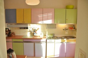 A kitchen with pastel-colored cabinets, a stainless steel sink, and a window allowing natural light. - Spacious, Cozy Apartment with Large Balcony, Rhine View & Piano (Bacharach)