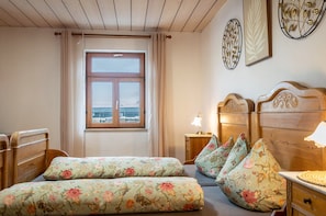 Un dormitorio con una cama de madera, una mesita de noche con lámpara, una ventana con cortinas y una pared decorada.