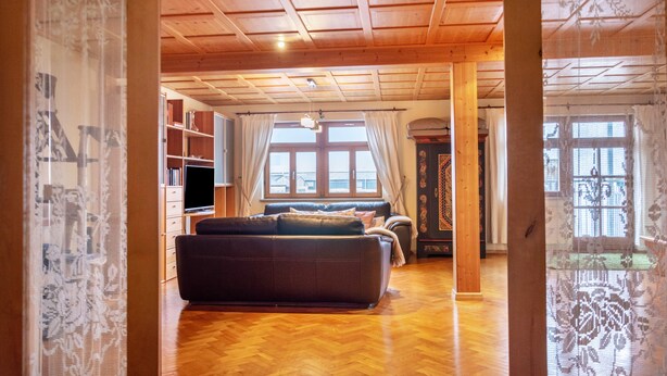 Una habitación con techo de madera, un sofá, un televisor y una estantería.