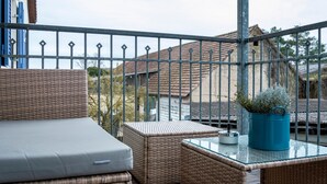 Un balcón con muebles de mimbre, una mesa de vidrio y una planta en maceta.