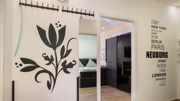 Un interior moderno con un adhesivo floral en la pared, un banco y una lista de nombres de ciudades.