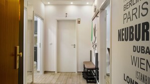 Un pasillo con una puerta de madera, un banco y una pared con nombres de ciudades.