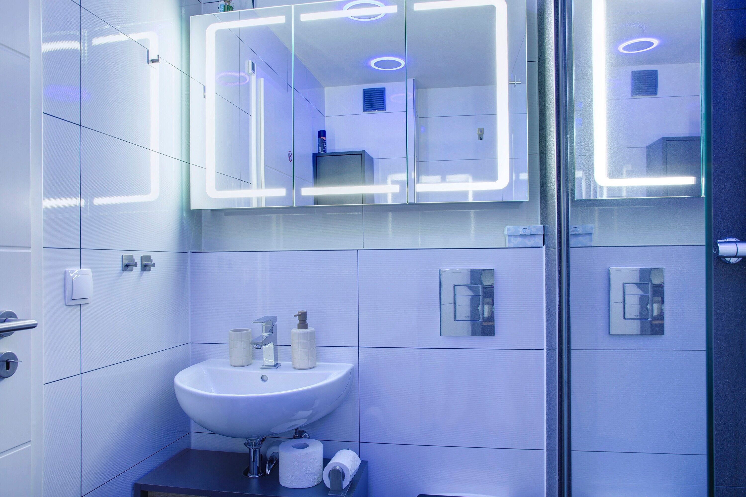 Un baño moderno con un espejo grande, un lavamanos y un inodoro.