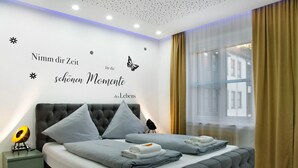 A bedroom with a bed, pillows, a nightstand, a wall decoration, and a window with curtains. - Apartment 'Neuburg 1 - New' with Wi-Fi (Neuburg an der Donau)