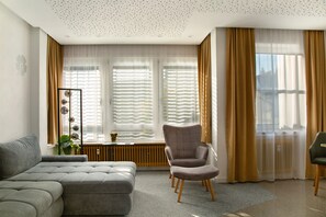 A modern living room with a grey sofa, a grey armchair, and a small table with a plant.