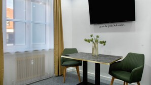 A room with a large window, a flat-screen TV mounted on the wall, a table with chairs, and a vase with flowers on the table. - Apartment 'Neuburg 1 - New' with Wi-Fi (Neuburg an der Donau)