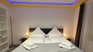 A hotel room with a large bed, two bedside tables with lamps, a ceiling light, and a built-in shelf.