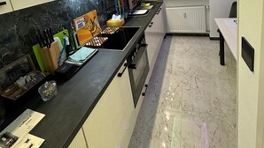 A modern kitchen with a black countertop, white cabinets, and a window with a potted plant.
