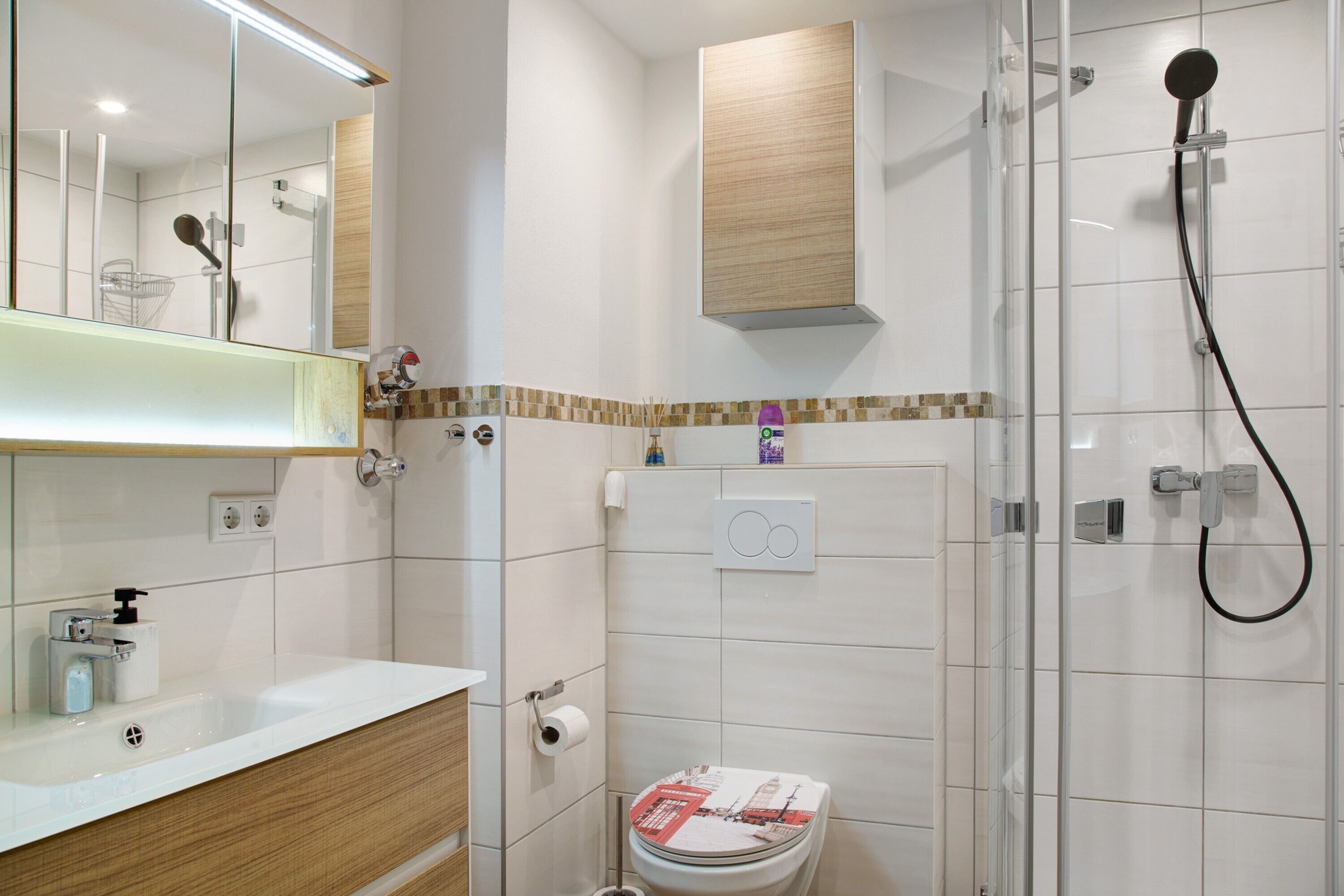 Een moderne badkamer met douche, toilet en wastafel.