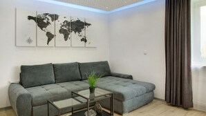 Ein modernes Wohnzimmer mit einem grauen Sofa, einem Glastisch und einer Weltkarte als Wandkunst.