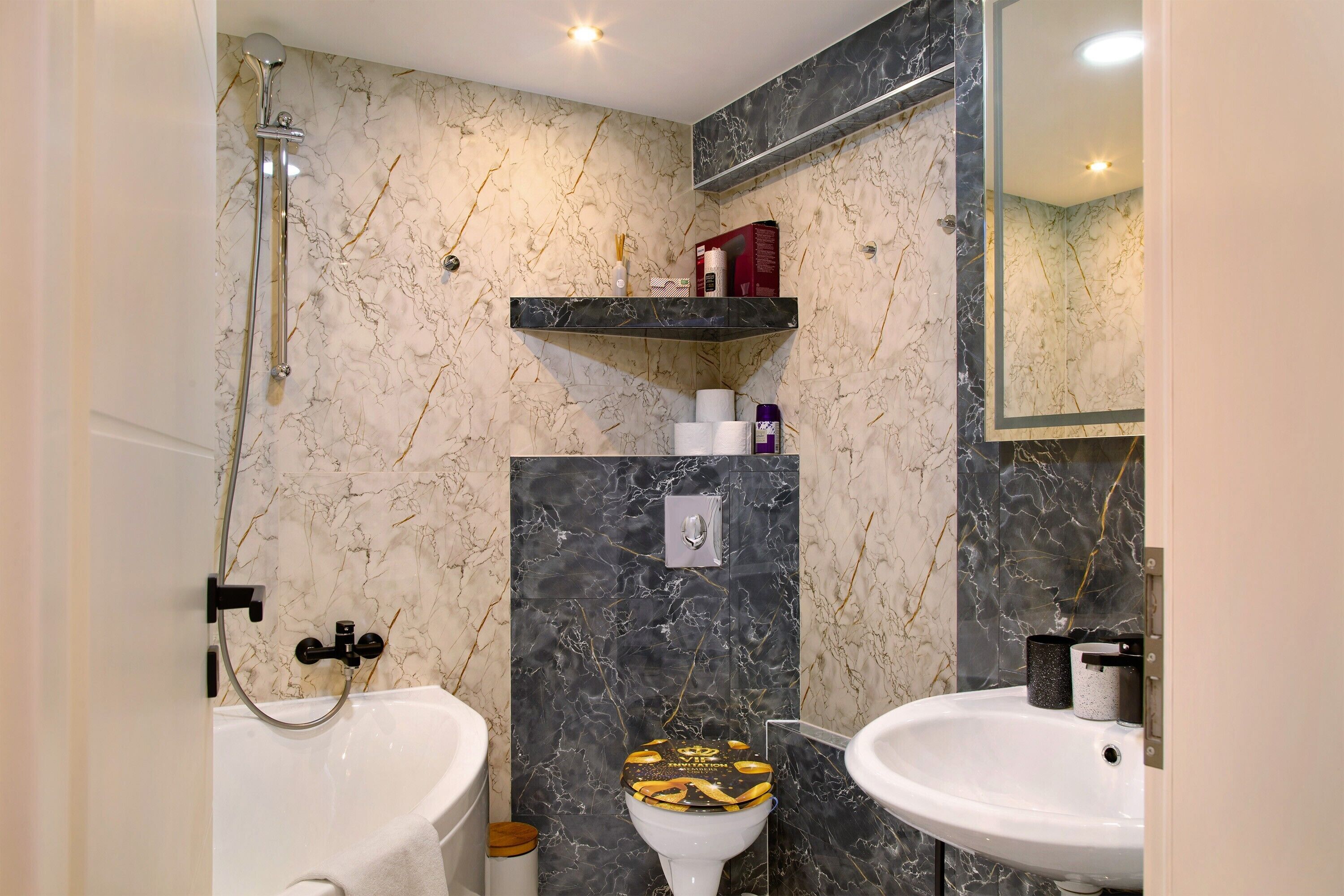 Ein Badezimmer mit Dusche, zwei Waschbecken, Toilette und Marmorwänden.