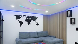 Una sala de estar moderna con un sofá gris, una mesa de centro colorida, un mural de un mapa mundial y un panel de pared de listones de madera.