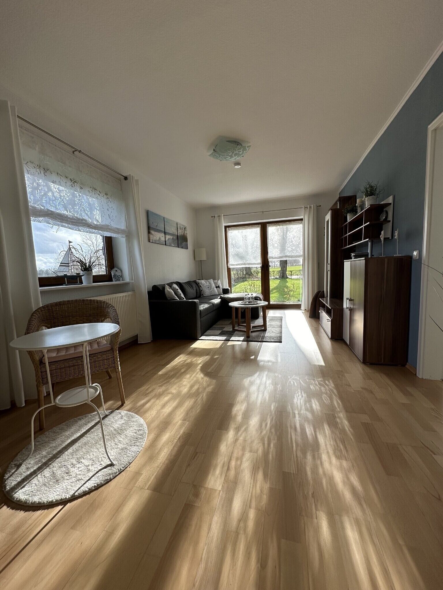 A spacious living area with a sofa, a dining table, and a view of the outdoors.