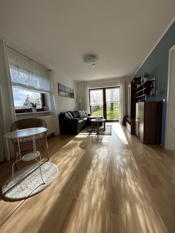 Ett rymligt vardagsrum med en soffa, ett matbord och utsikt över omgivningarna.