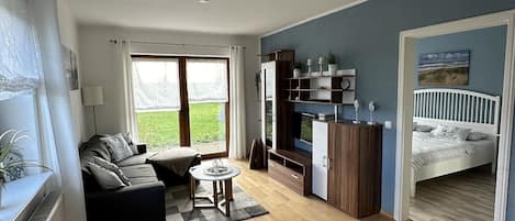 Amplia sala de estar con sofá, una mesa de comedor y una zona de cocina con armarios y televisor.