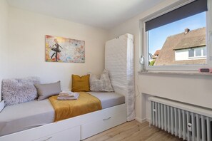 Une chambre à coucher avec un lit, une fenêtre, un radiateur et un tableau accroché au mur.