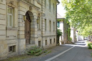 Un bâtiment historique en pierre, doté d’une grande porte en bois, de nombreuses fenêtres et situé dans une rue étroite.