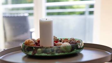 A candle in a bowl on a table with a window in the background.