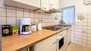 A kitchen with white cabinets, a stove, a coffee maker, and a window with a view. - Apartment 'Groth's' with Shared Terrace, Shared Garden and Wi-Fi (Lunden)