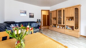A living room with a wooden table, a sofa, a cabinet with glass doors, and a vase with flowers. - Apartment 'Groth's' with Shared Terrace, Shared Garden and Wi-Fi (Lunden)