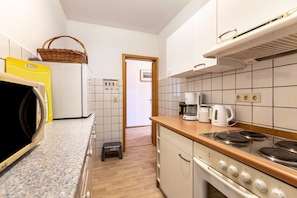 Una cocina compacta equipada con microondas, tostadora, cafetera y estufa.