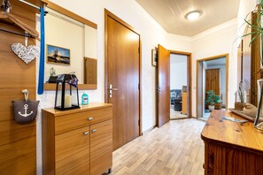 Een gang met houten kasten, een spiegel en een deur naar een andere kamer.