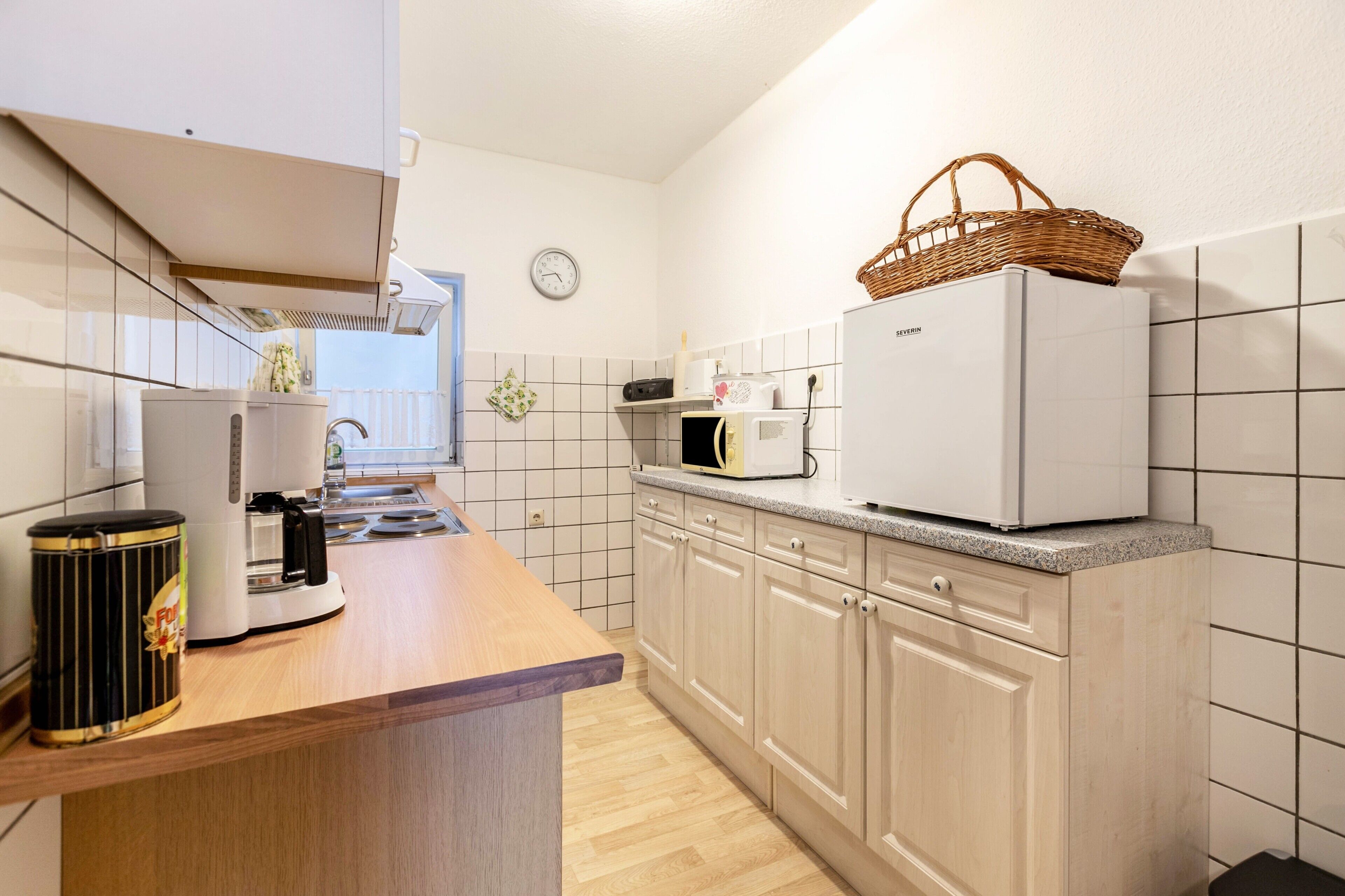 Een moderne keuken met een houten aanrecht, een witte koelkast, een magnetron en een koffiezetapparaat.