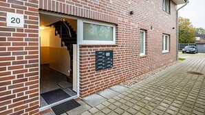 A brick building with a number '20' sign, a staircase, and a mailbox.