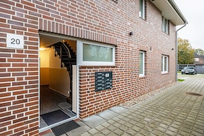 Un bâtiment en briques avec le numéro « 20 » affiché, un escalier et une boîte aux lettres.