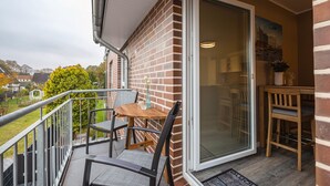 A balcony with a table and chairs, a sliding glass door, and a view of the surrounding area.