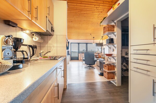 Una cocina moderna con armarios de madera, una cafetera y un comedor con una silla y una mesa.