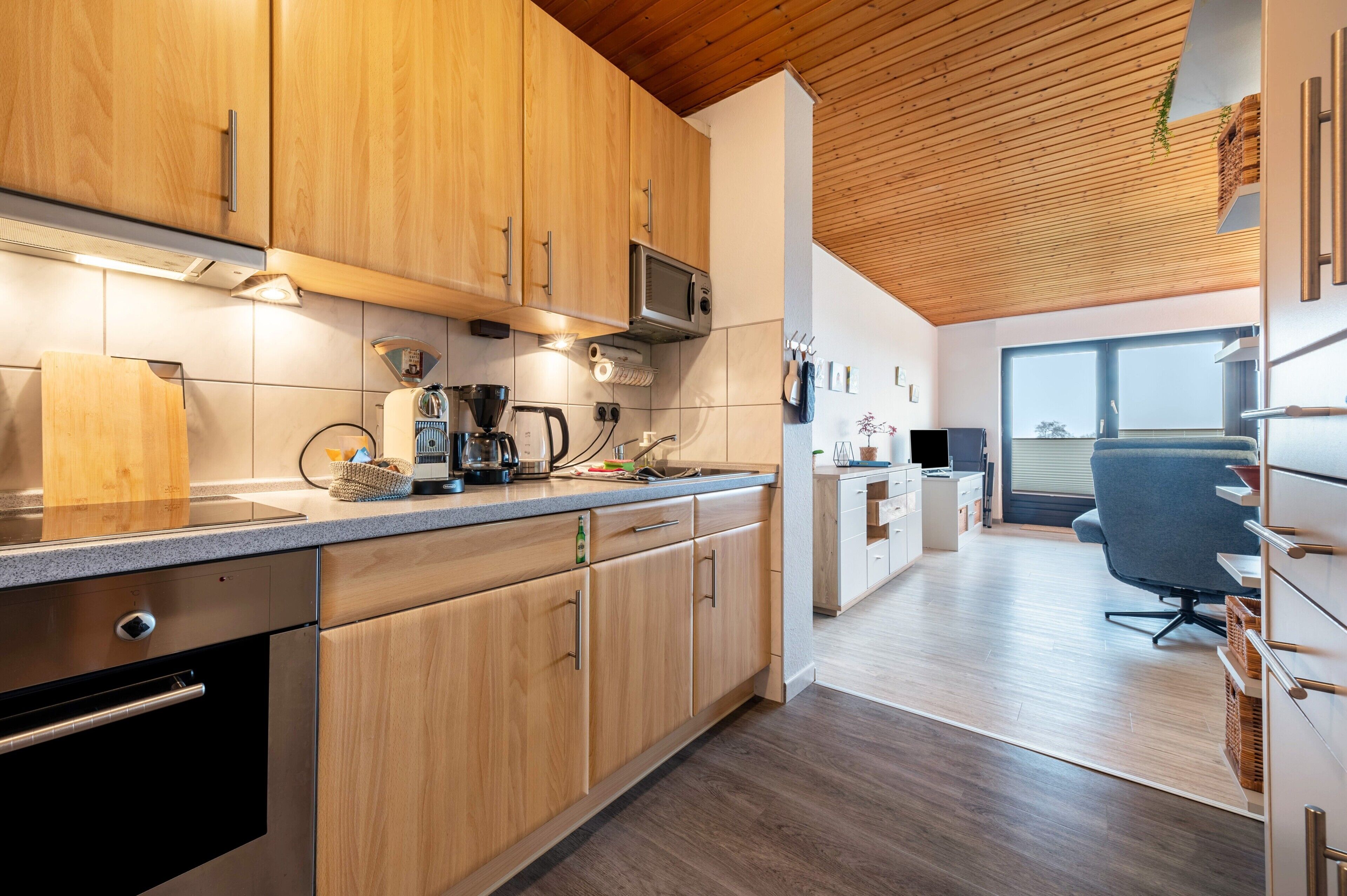 A modern kitchen with wooden cabinets, a microwave, and a coffee maker.
