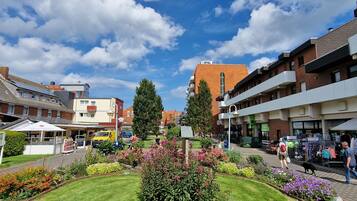 A hotel with a red roof, a garden with various plants, and a clear blue sky.